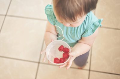 Toddler holding bowl of fruit
